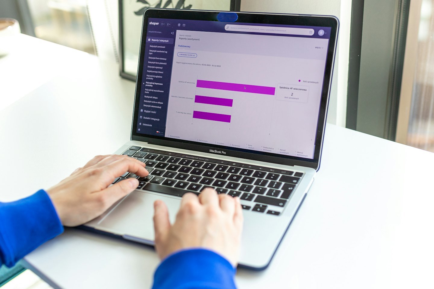 Hands typing on a silver MacBook Pro showing analytics.