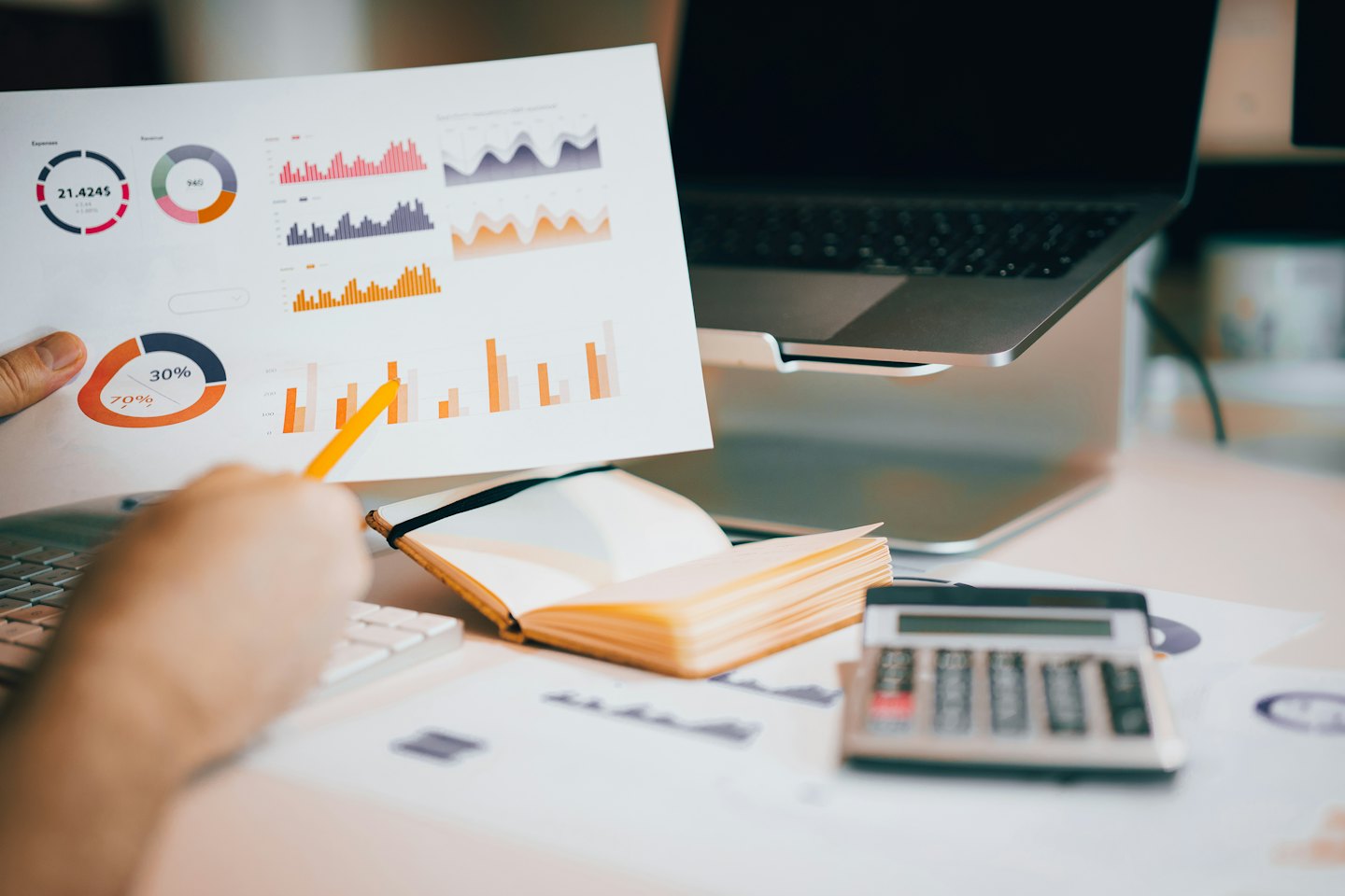 Person analyzes business data charts with a yellow pencil on a desk.